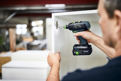 Person using a Festool cordless impact drill to install cabinet hardware in a home improvement setting