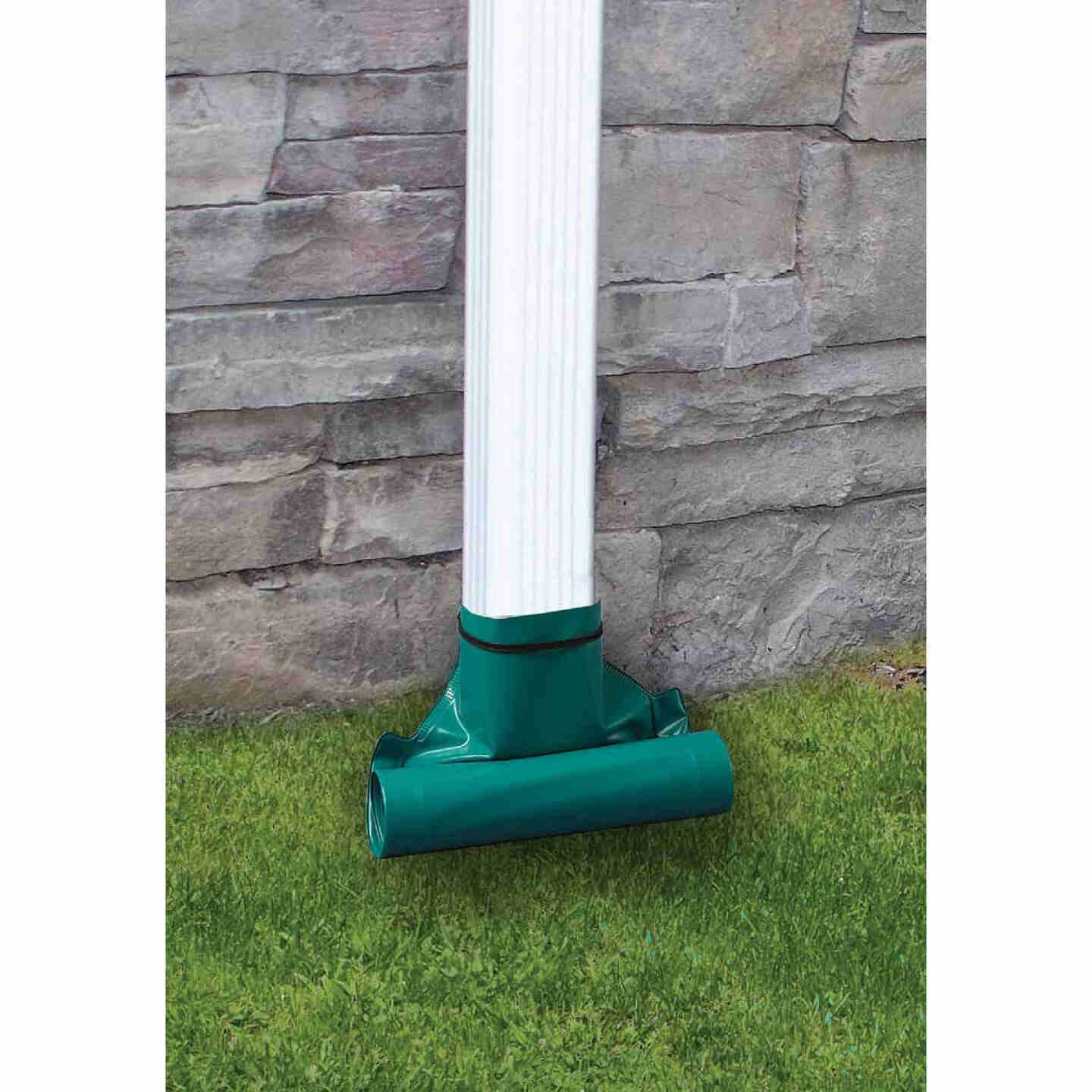 Green plastic downspout extender attached to white downspout directing water onto grassy ground for home use