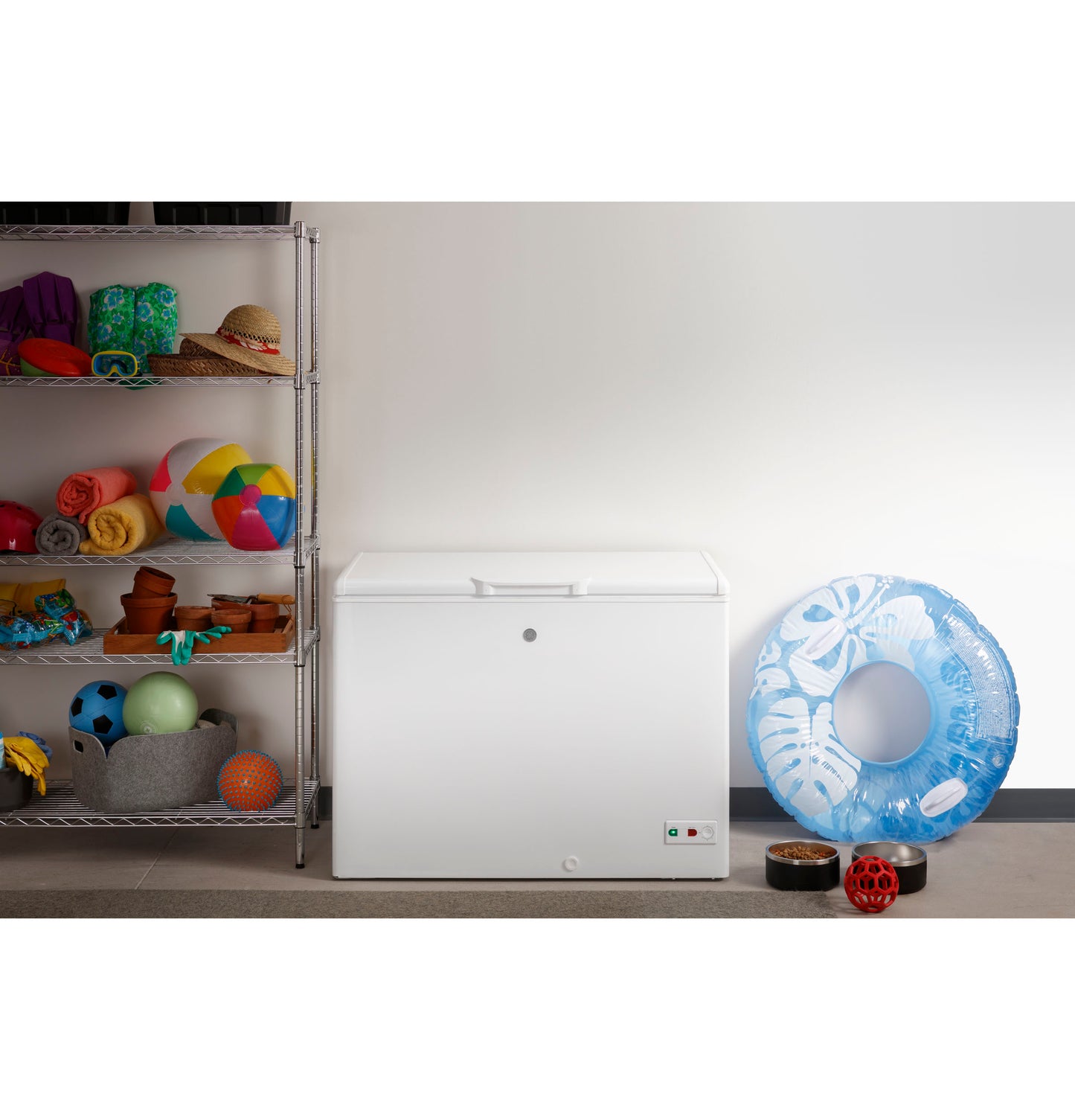 White manual defrost chest freezer in garage with storage shelves and pool toys nearby in home improvement setting