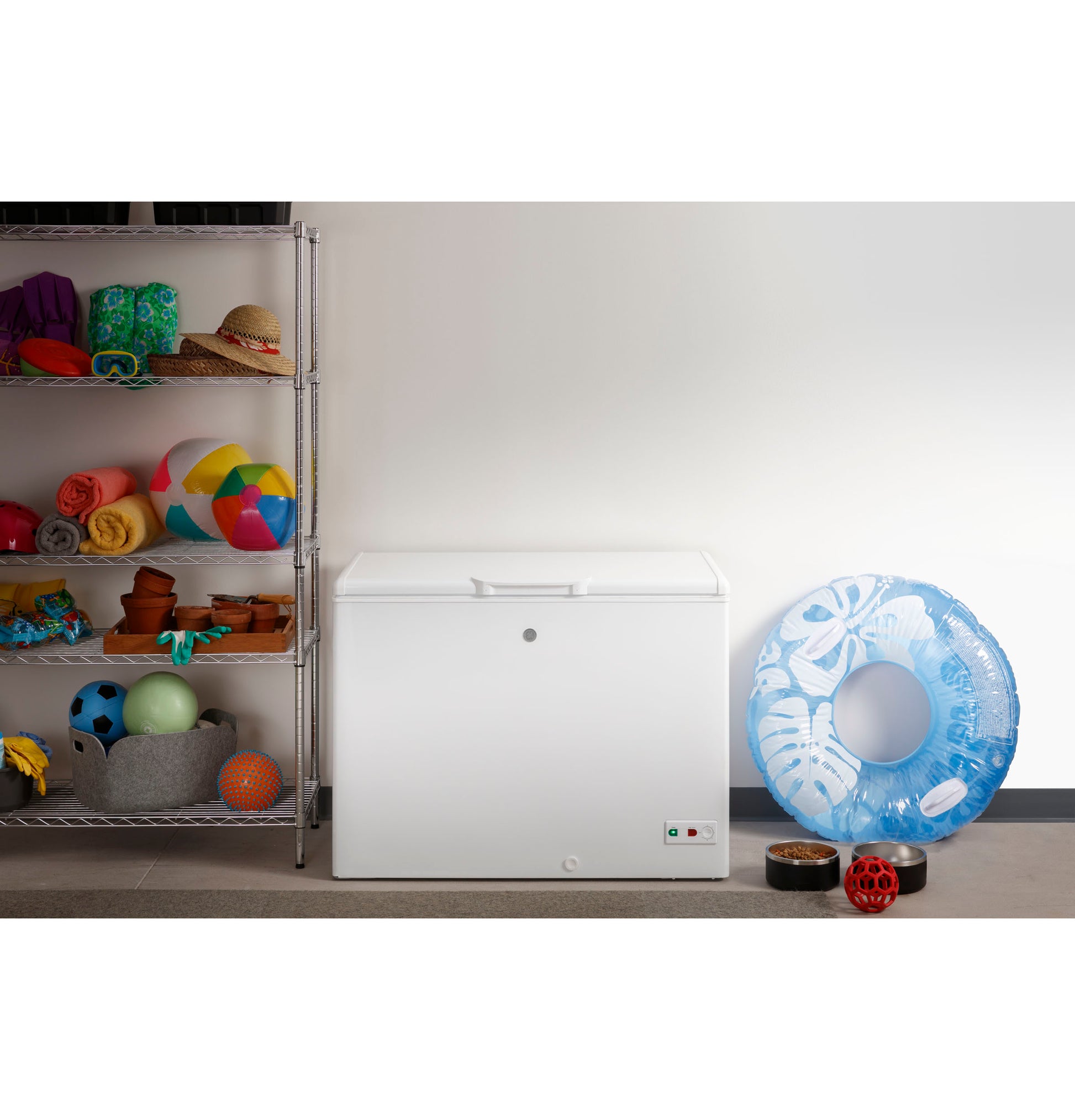 White manual defrost chest freezer in garage with storage shelves and pool toys nearby in home improvement setting