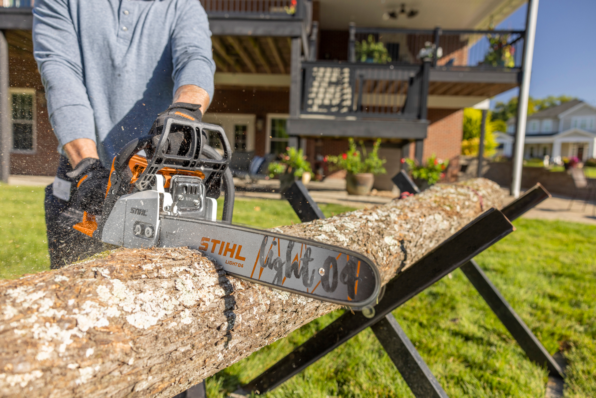 Orange and gray high-performance compact gas chainsaw cutting a large log outdoors for home improvement tasks