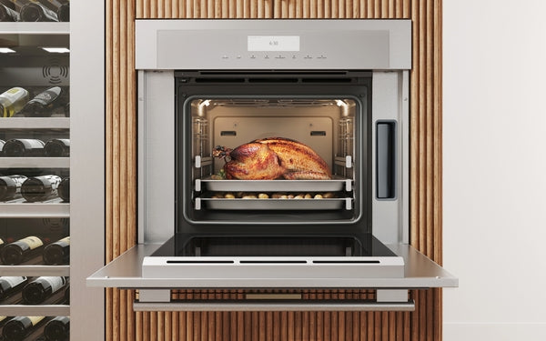 Stainless steel single wall oven with open door showing roasted turkey on rack inside modern kitchen setting