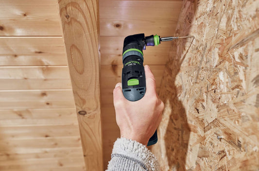 Compact cordless drill with angled design driving a screw into plywood in woodworking and power tools setting