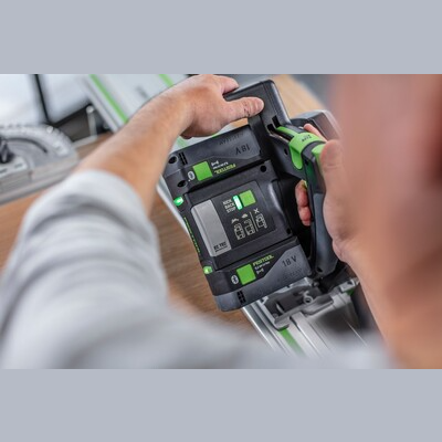 Person inserting battery into Festool cordless track saw on guide rail for power tools and home improvement