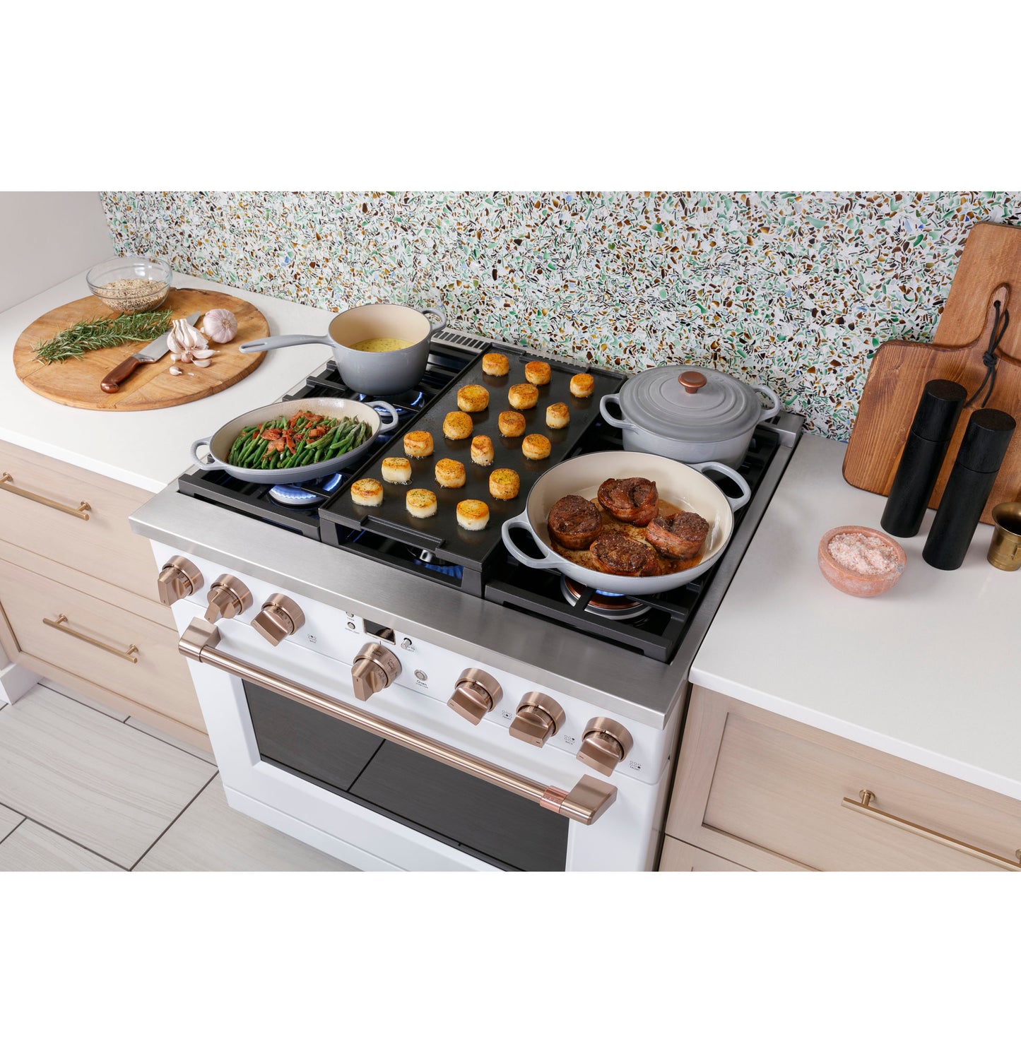 White smart gas range with six burners cooking vegetables, sauce, and meat, set in a modern kitchen counter space