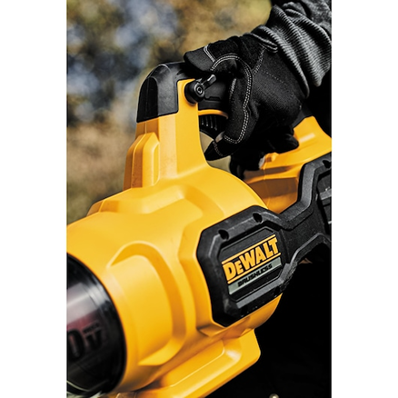 Hand gripping the handle of a yellow DEWALT cordless axial blower in an outdoor setting for home improvement use