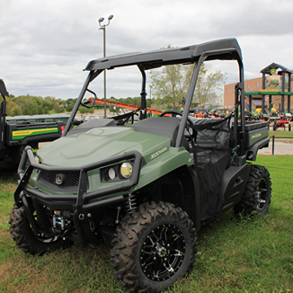 Green mid-size utility vehicle with rugged off-road tires and front brush guard for outdoor work and home improvement tasks