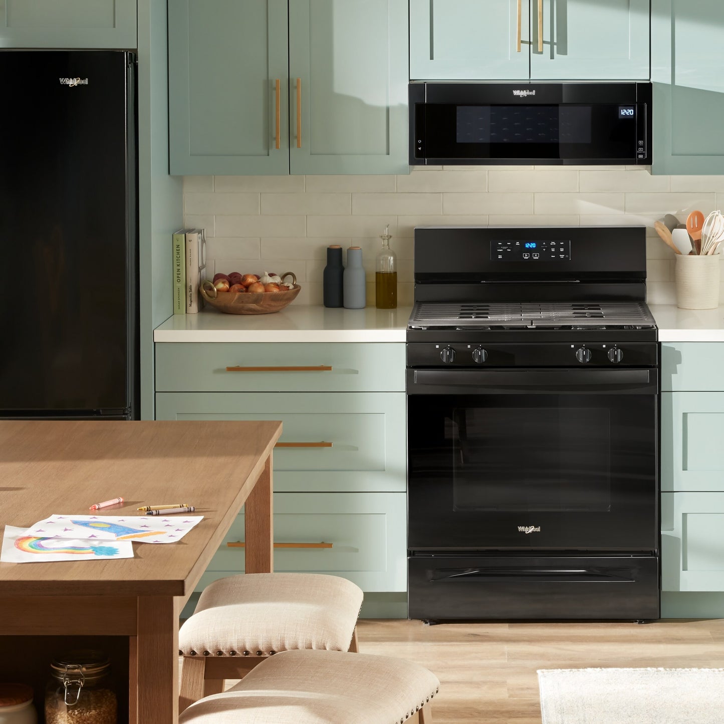 Black freestanding gas range with digital control panel installed in a kitchen with green cabinetry and wood accents