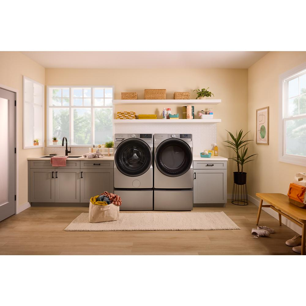 Laundry room with smart front load gray electric washer and dryer set near gray cabinetry and indoor plants