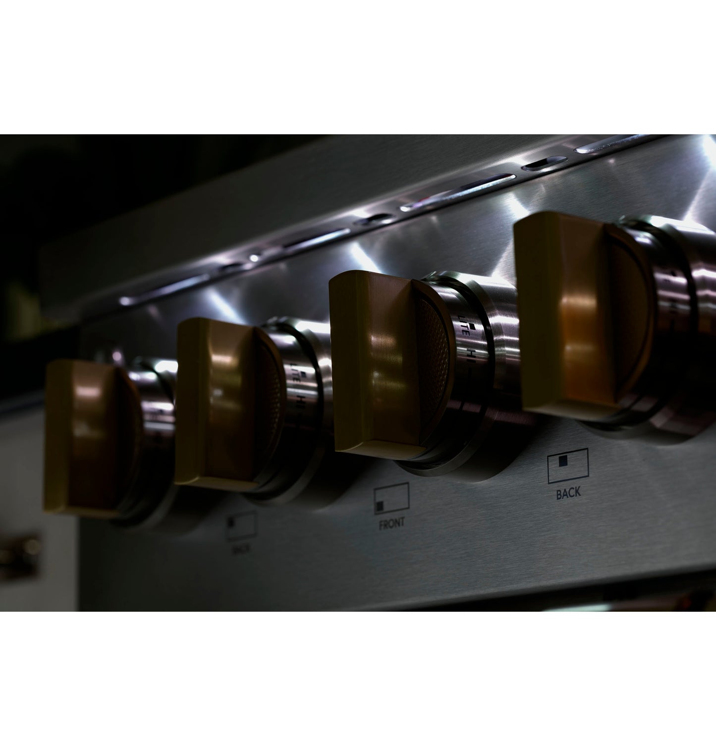 Close-up of brushed stainless steel control knobs on a professional gas rangetop in a modern kitchen setting