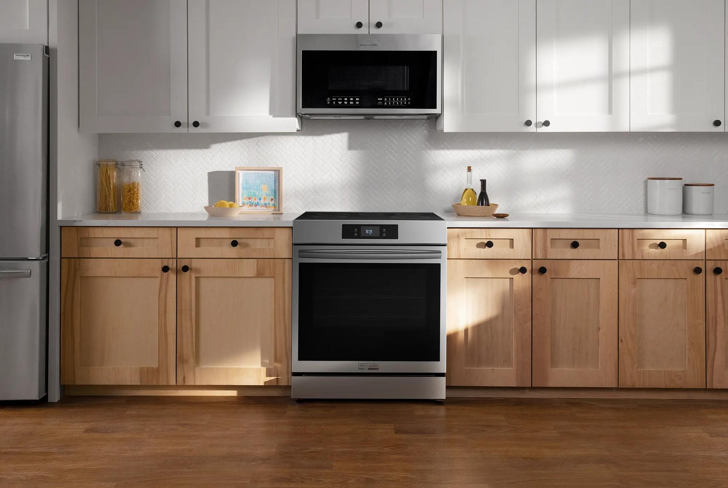 Modern kitchen with stainless front control induction range and microwave installed above, surrounded by wood cabinets