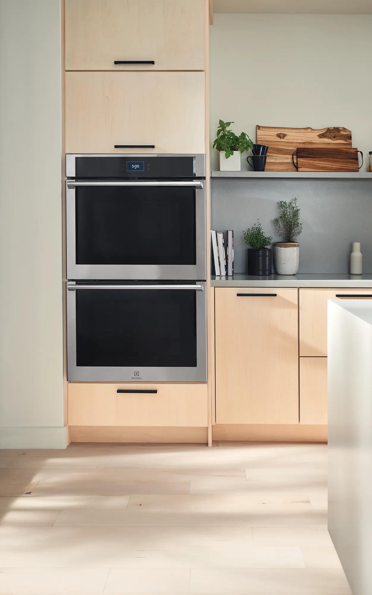 Built-in stainless steel double wall oven with digital display in modern kitchen cabinetry and neutral decor setting