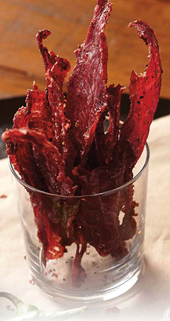 Thin strips of homemade beef jerky arranged in a clear glass for kitchen and snack preparation under $50 collections
