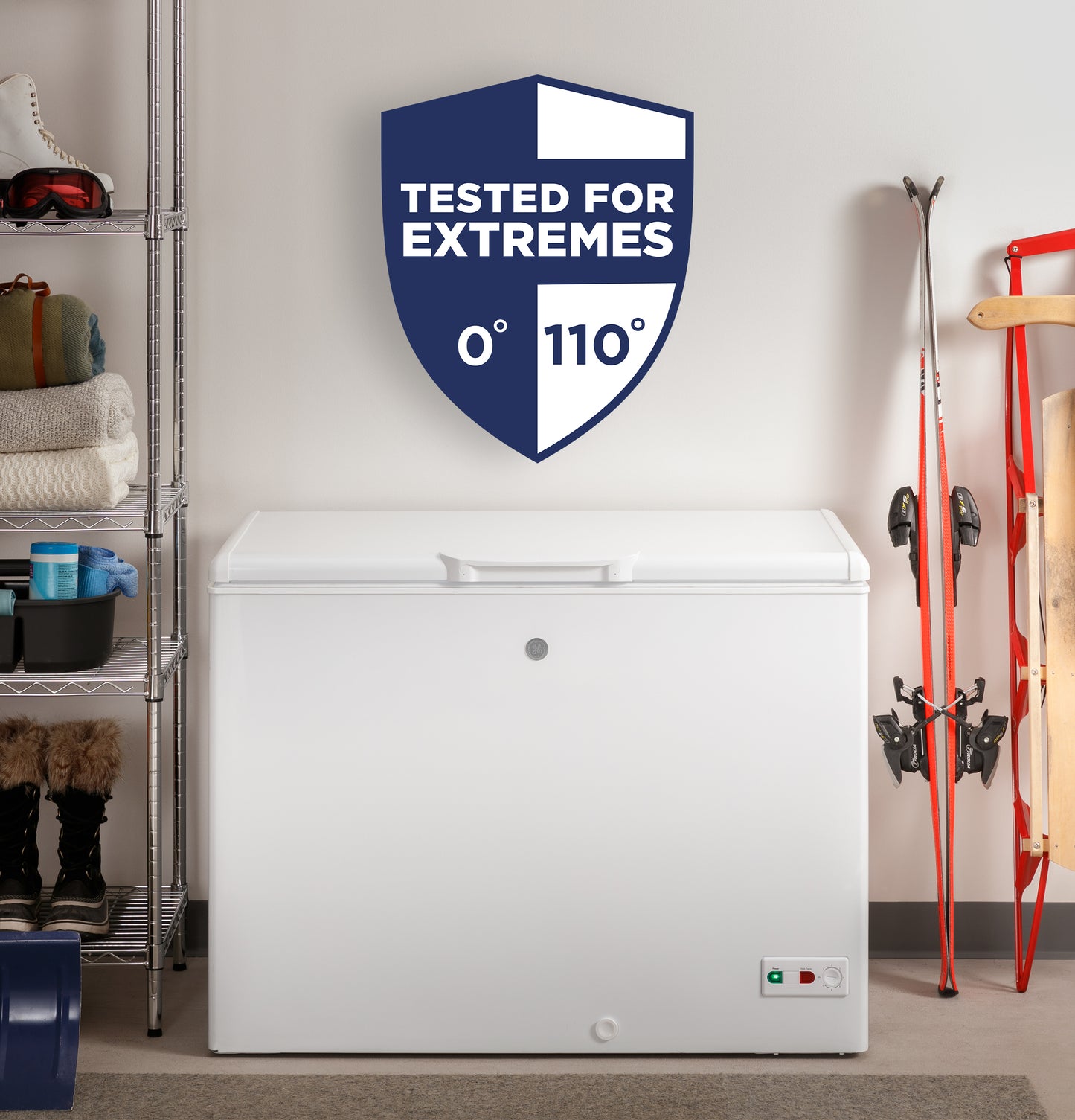 White manual defrost chest freezer in storage room with shelving, ski equipment, and extreme temperature tested sign above