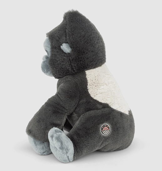 Plush gorilla toy with dark gray fur and light gray face, hands, feet, and white patch on back sitting on gray surface