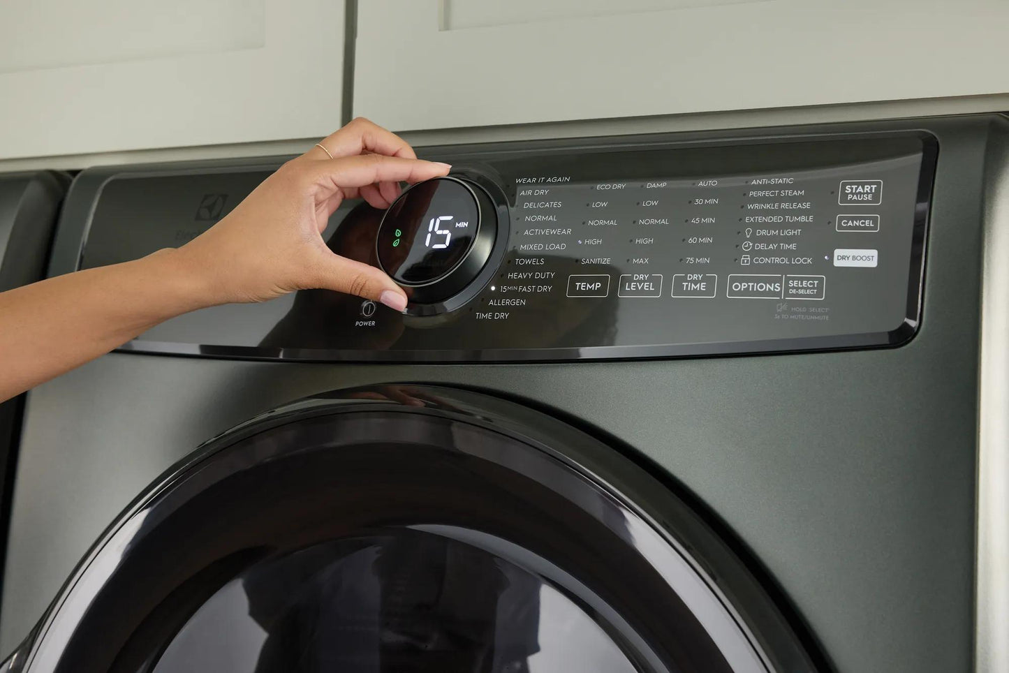 Hand adjusting digital control dial on dark gray front load washer from washers and appliances collection