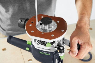 Person adjusting a Festool router accessory on a workbench for precise woodworking and home improvement tasks