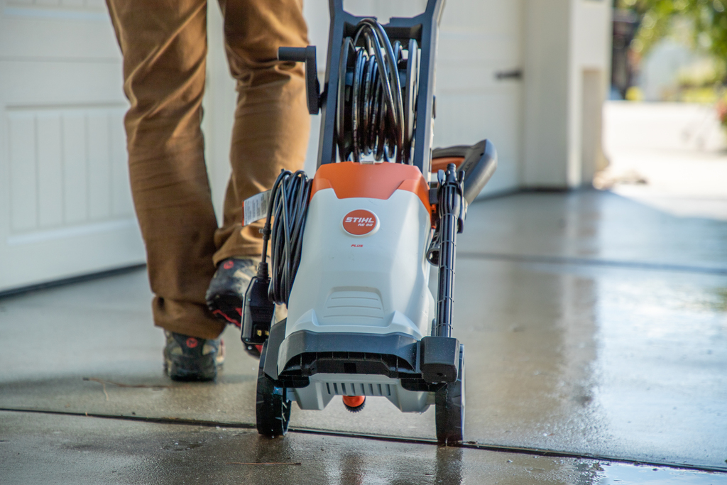 White and orange STIHL RE 90 Plus pressure washer with hose reel and wheels for efficient outdoor cleaning tasks