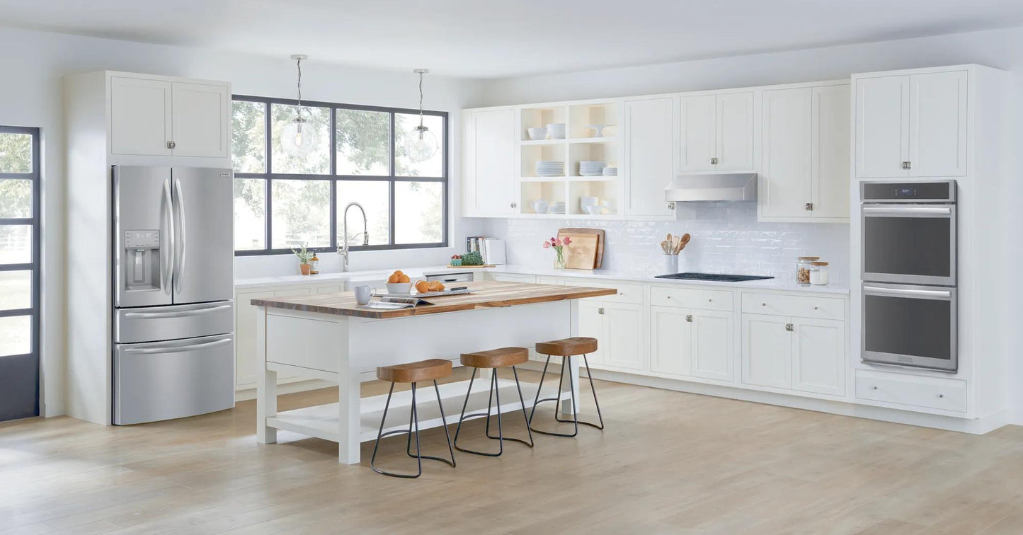 Modern white kitchen featuring stainless steel double electric wall oven, French door refrigerator, and island seating in bright space