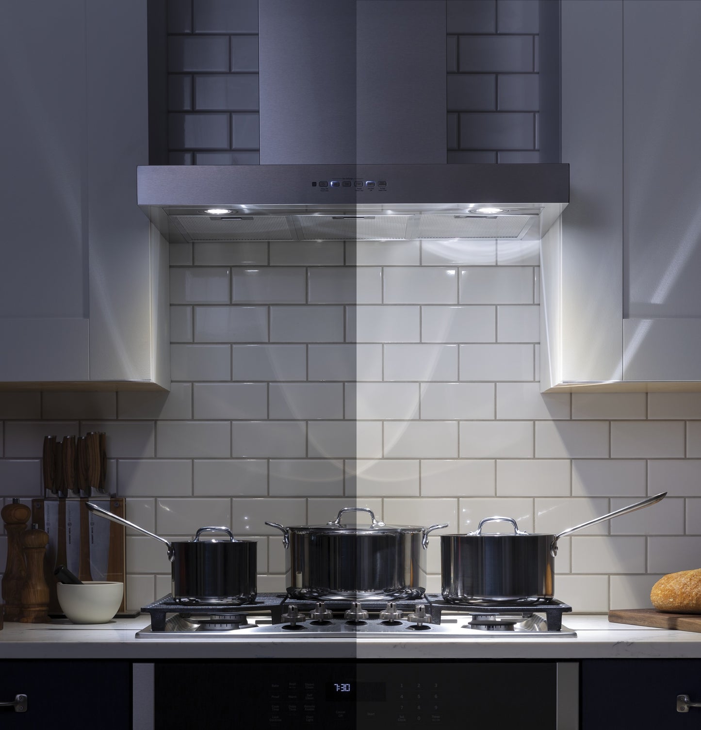 Stainless steel wall mount range hood with dimmable LED lights above a gas cooktop in a modern kitchen setting