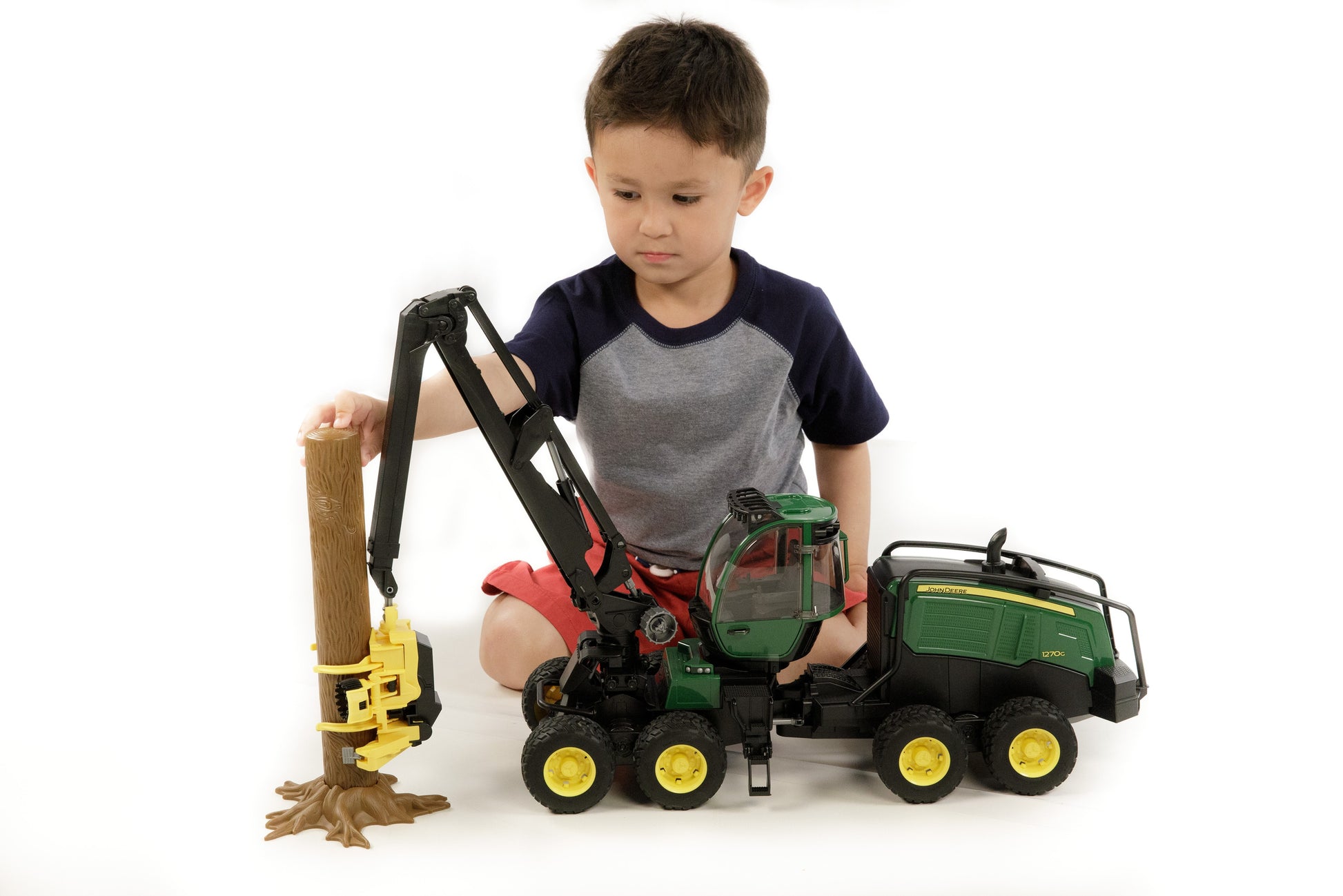 Child playing with detailed Bruder Toys green and yellow wheeled harvester holding log in Toys & Games collection