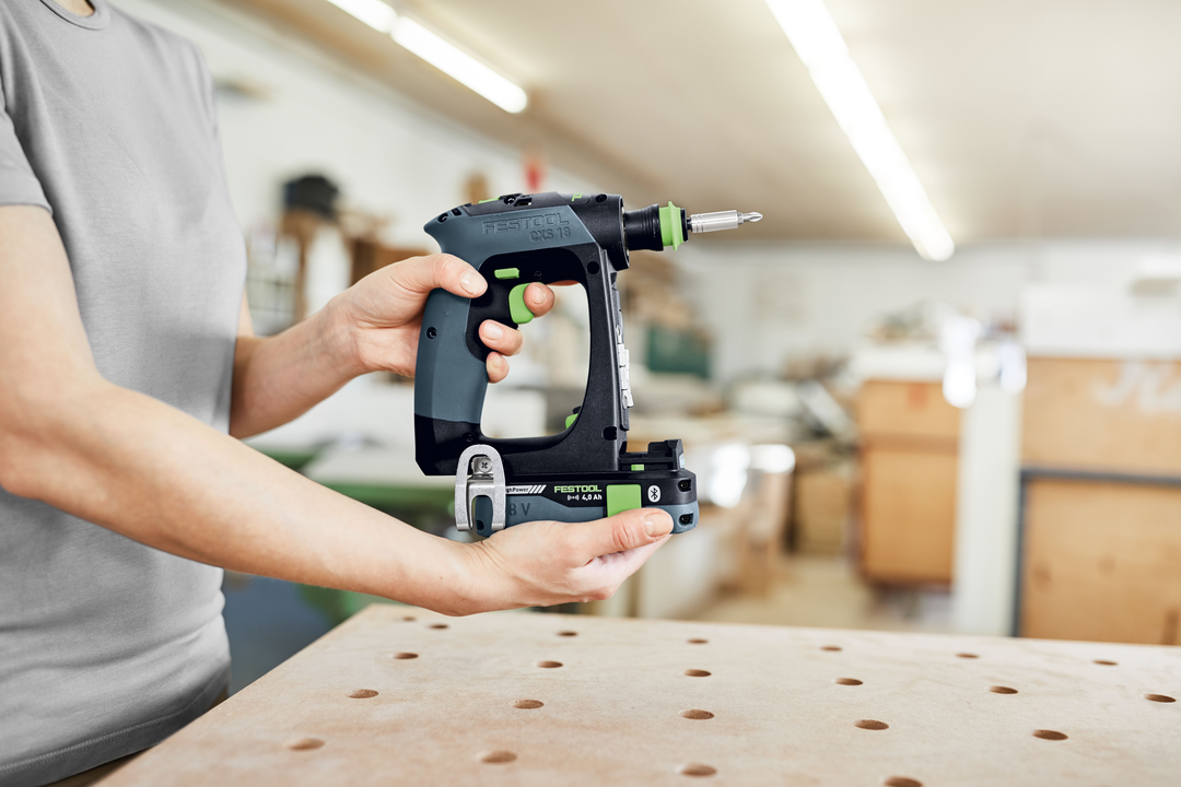 Person holding Festool cordless drill with ergonomic grip for woodworking and power tools in workshop setting
