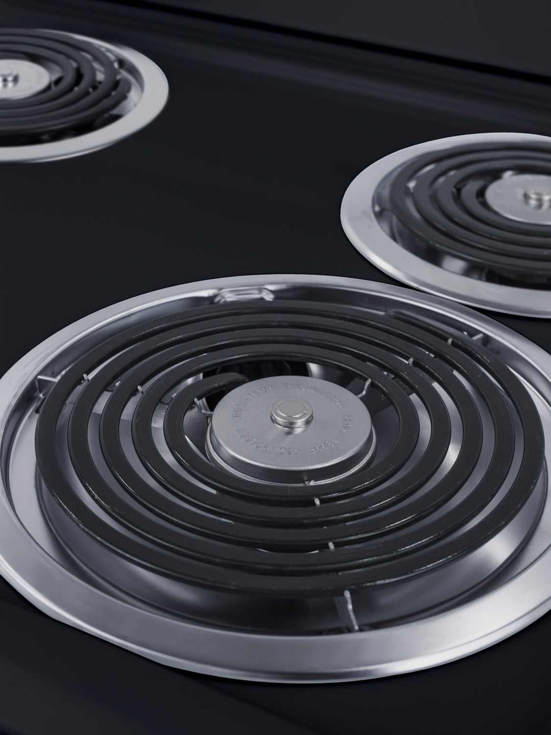 Close-up view of black electric coil burners with silver trim on a 24" wide electric range cooktop surface