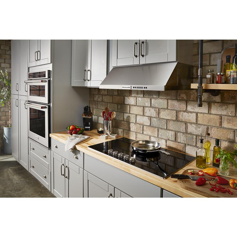 Modern kitchen setup with a sleek electric cooktop, stainless steel hood, and double wall ovens in home improvement appliances collection