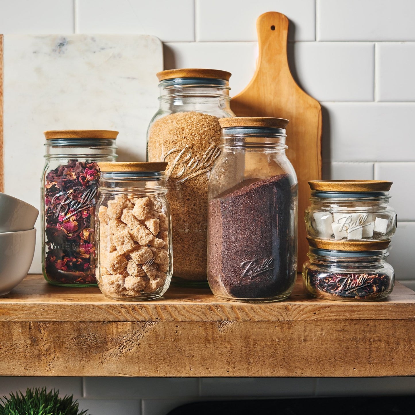 Clear glass jars with wooden lids storing assorted dry ingredients on a kitchenware shelf under $50 collection