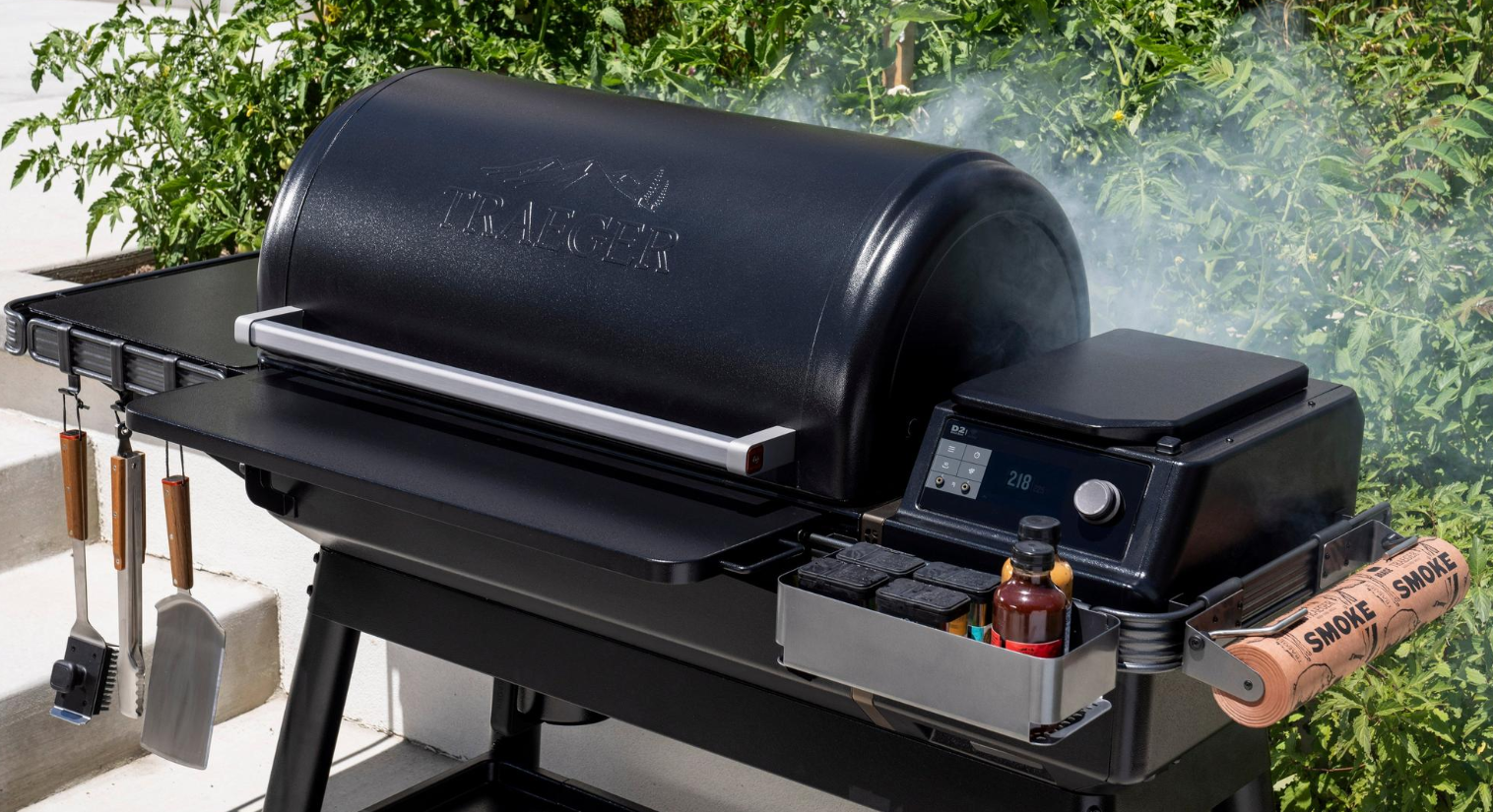 Black Traeger IronWood XL pellet grill with WiFIRE® control panel and wood smoke pellets in outdoor living setting