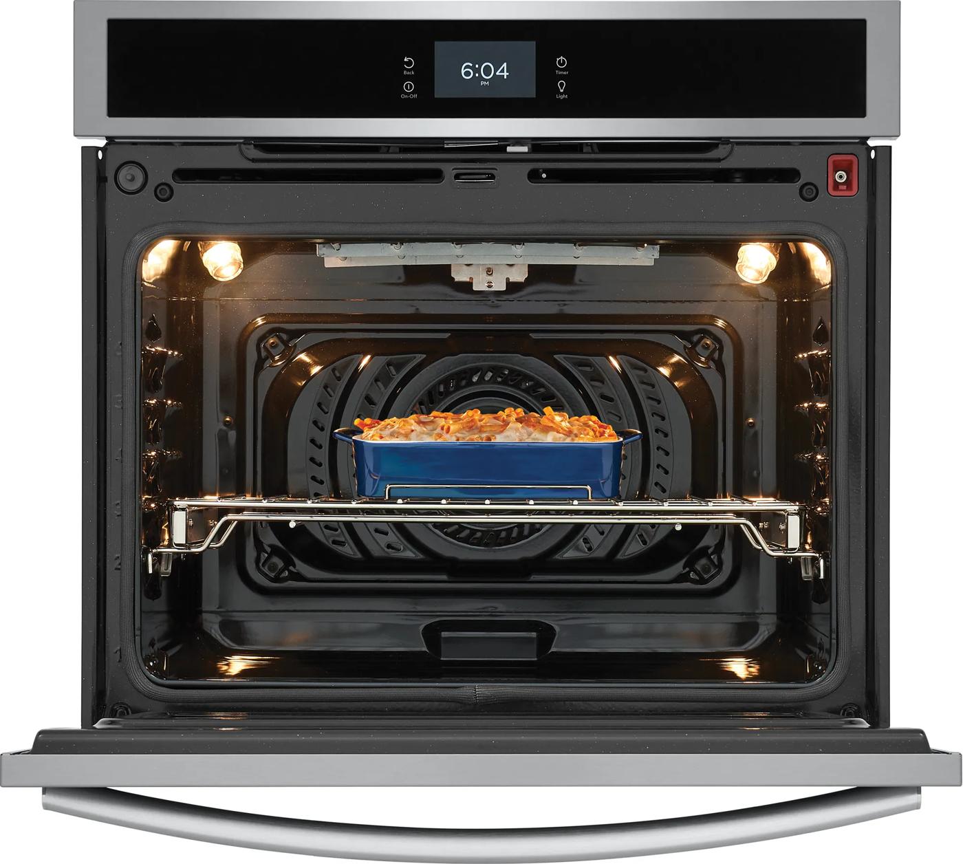 Stainless steel electric wall oven with convection system cooking casserole inside in kitchen appliances collection