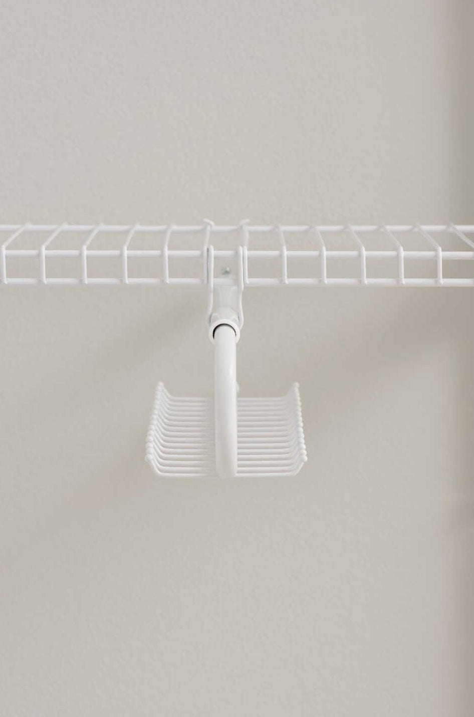 White metal tie and belt organizer hanging from a wire closet shelving in storage and closet organization setting