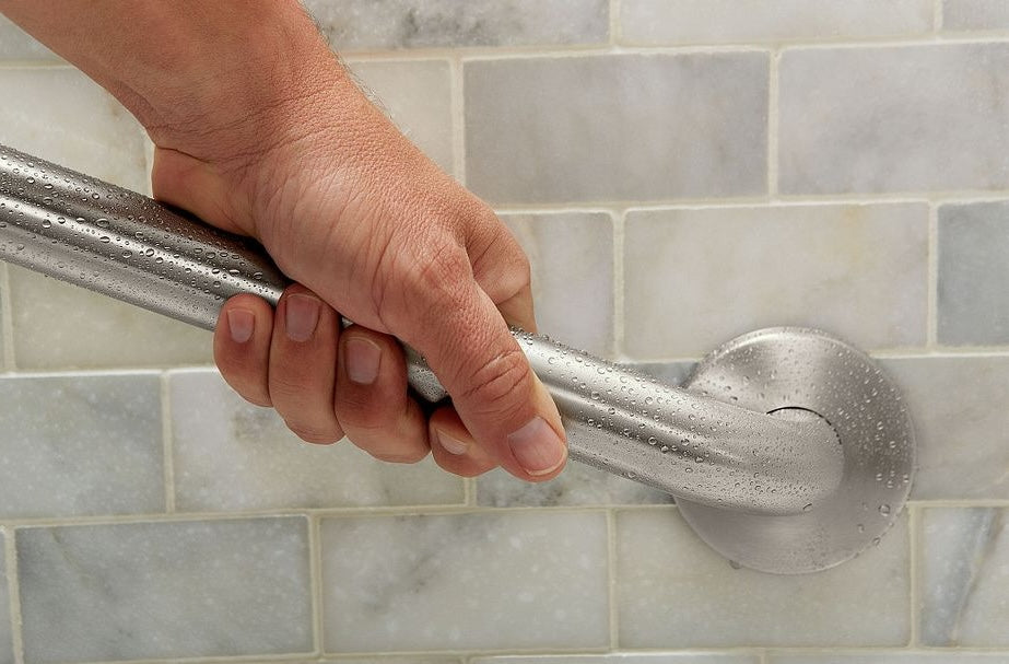 Hand gripping stainless steel grab bar with concealed mounting in bathroom shower for improved safety and accessibility