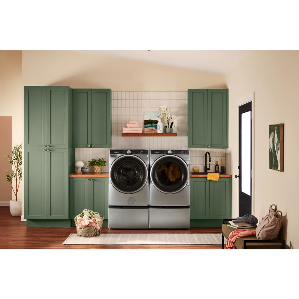 Modern laundry room with silver front load washer and smart electric dryer surrounded by green cabinetry and wooden countertops