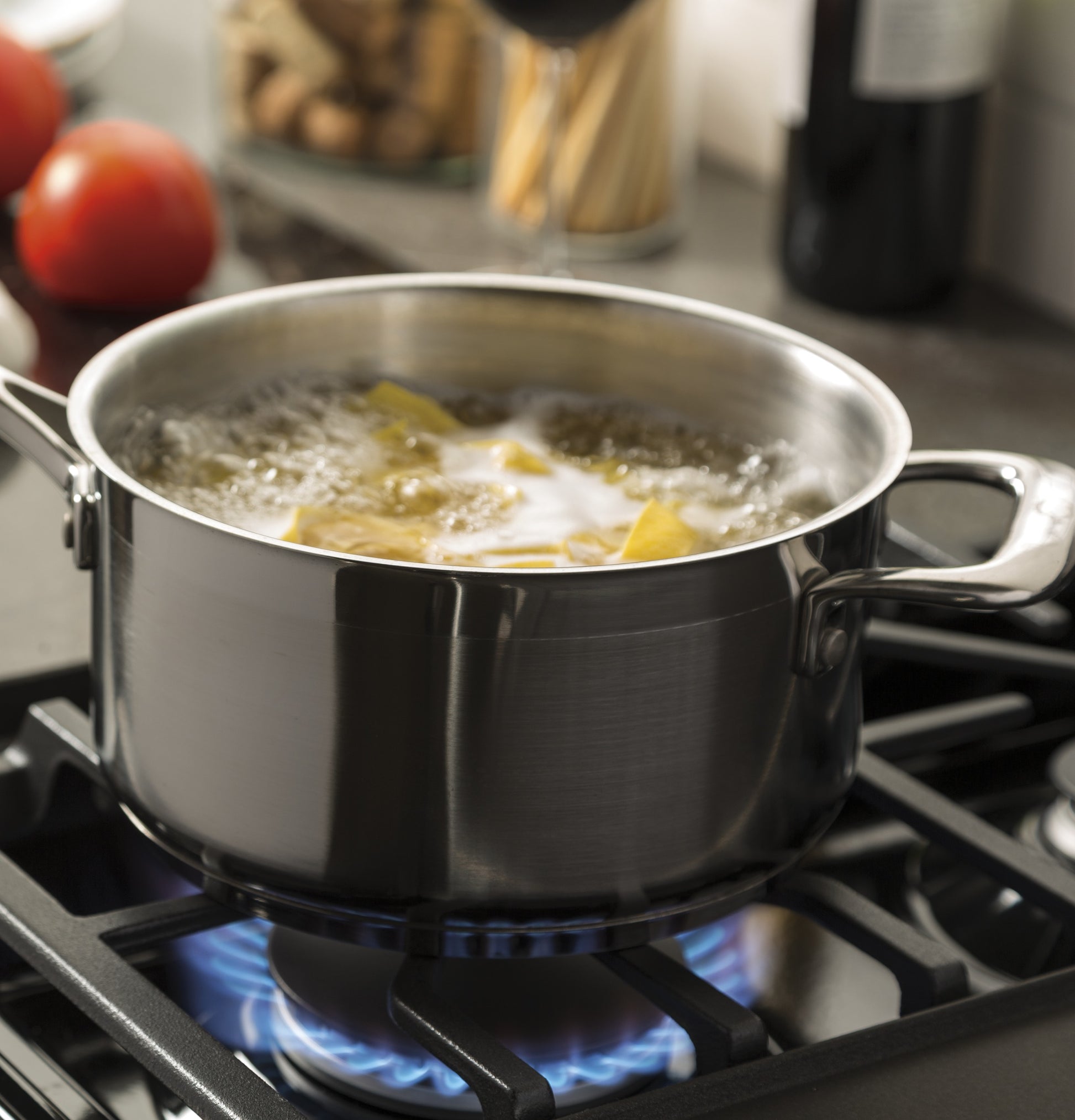 Stainless steel pot boiling water with pasta on a gas burner in a kitchen and home appliance setting