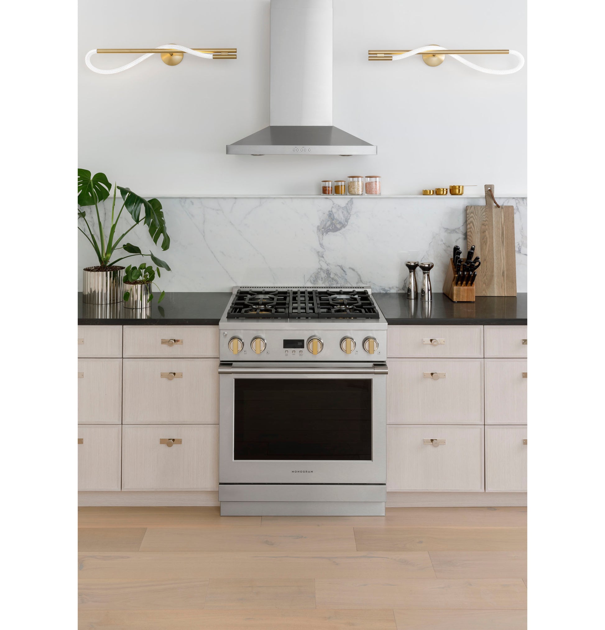 Contemporary stainless steel wall-mounted vent hood above gas range with marble backsplash and modern kitchen décor