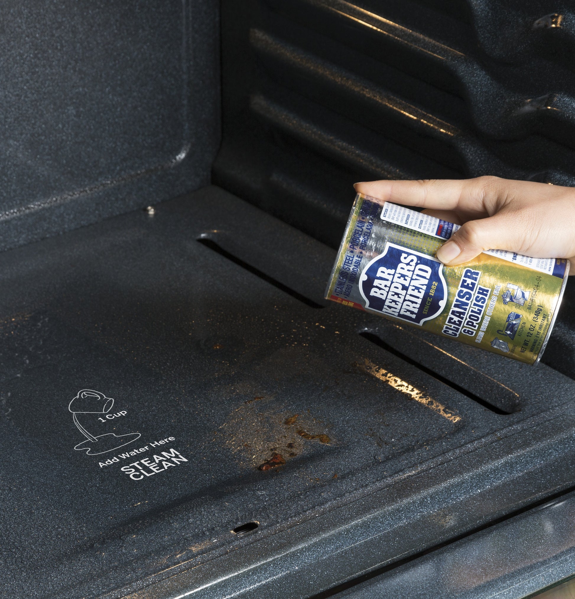 Hand pouring cleaner polish inside an oven cavity for steam cleaning in kitchen and home appliances setting