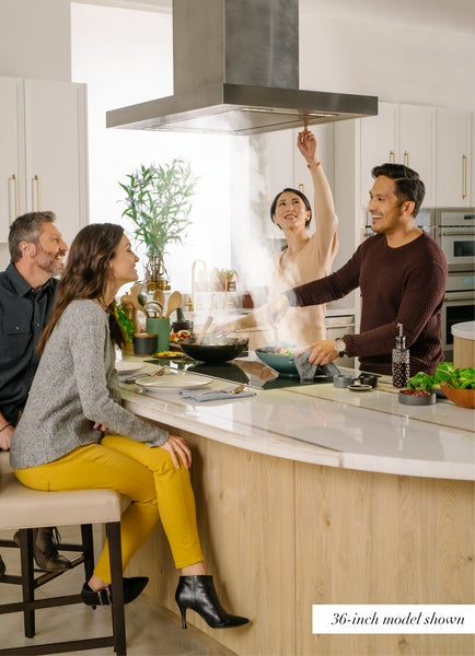 Four adults enjoying cooking and conversation around a modern kitchen island with stainless steel range hood above