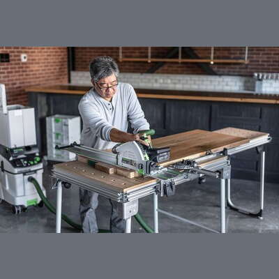 Person using Festool cordless track saw with kickback stop cutting wood on adjustable workbench for home improvement