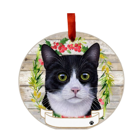 Round ceramic ornament with black and white cat face inside a festive wreath on rustic wood background