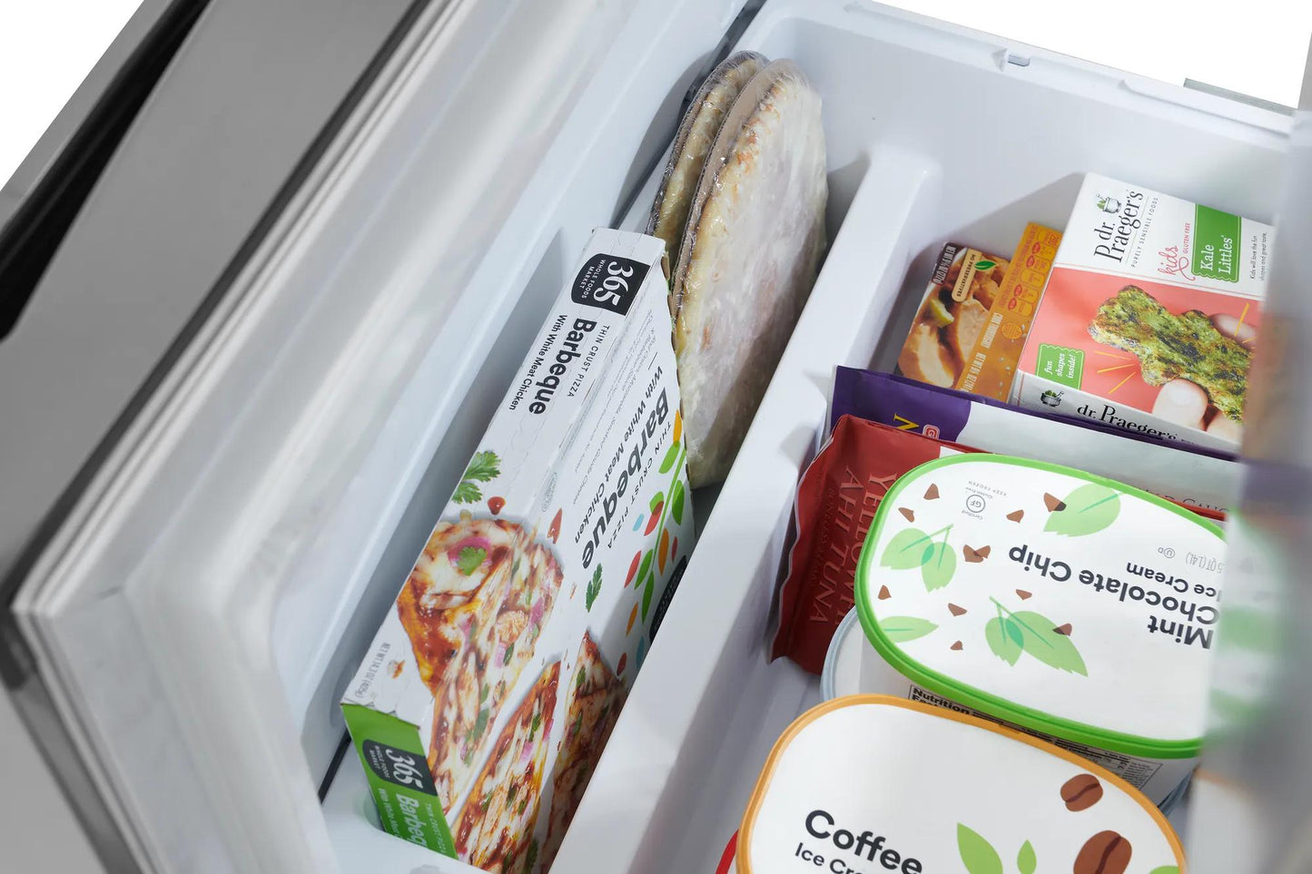 Open bottom freezer drawer showing organized frozen meals, ice cream, and packaged food in kitchen appliance setting