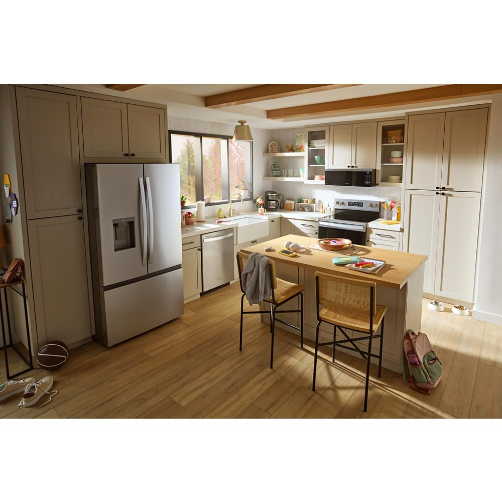 Modern kitchen with stainless steel refrigerator, beige cabinetry, wood floor, center island, and built-in dishwasher in appliances setting