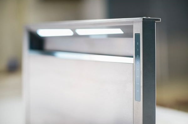 Close-up of stainless steel downdraft ventilation panel with control settings and built-in lighting for kitchen use