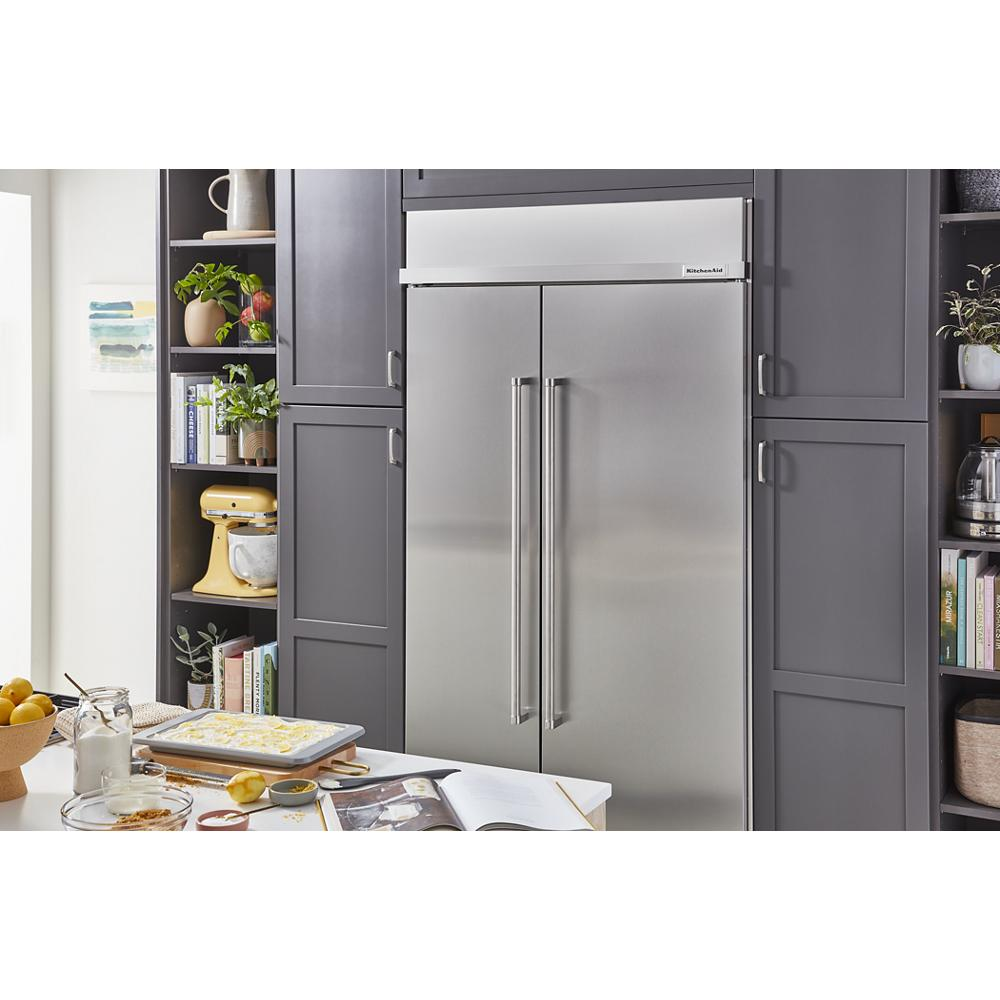 Stainless steel dual-door refrigerator integrated into dark gray cabinetry in a modern kitchen setting with baking items nearby