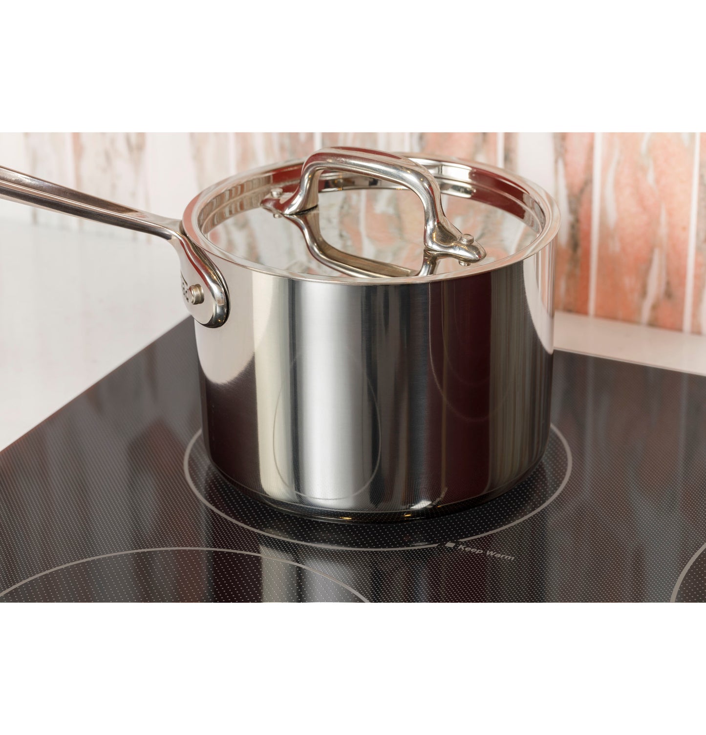 Stainless steel pot with lid on black smooth electric cooktop in modern kitchen setting and cooktops collection