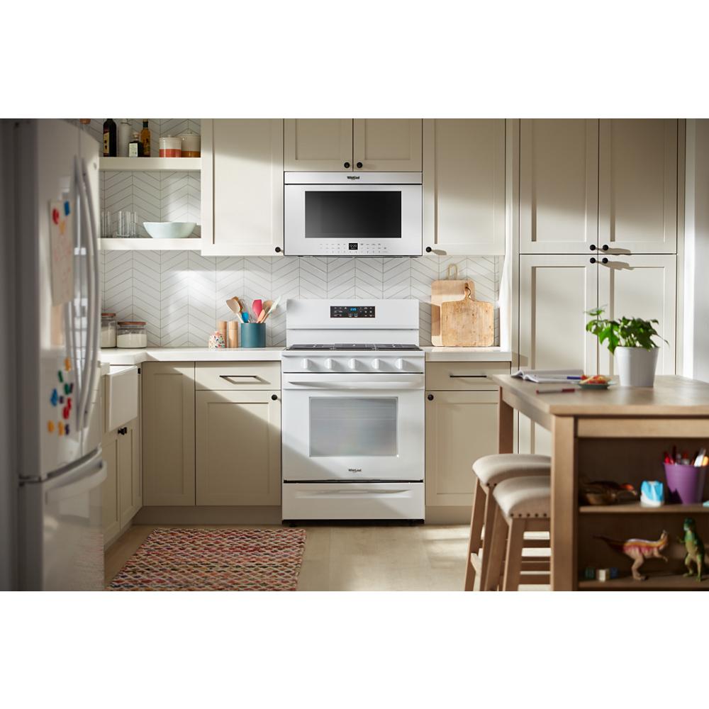Whirlpool white air fry microwave with flush built-in design installed above stove in beige kitchen setting