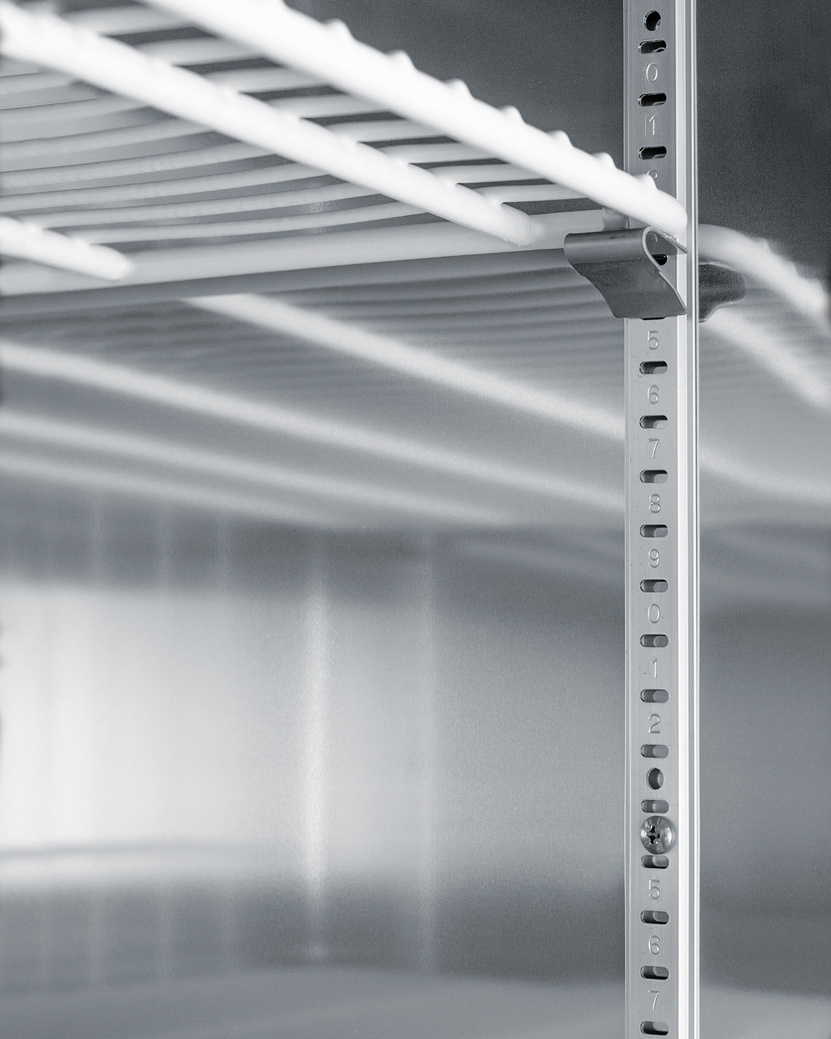Close-up of adjustable metal shelving inside a stainless steel pharmacy refrigerator in appliances collection