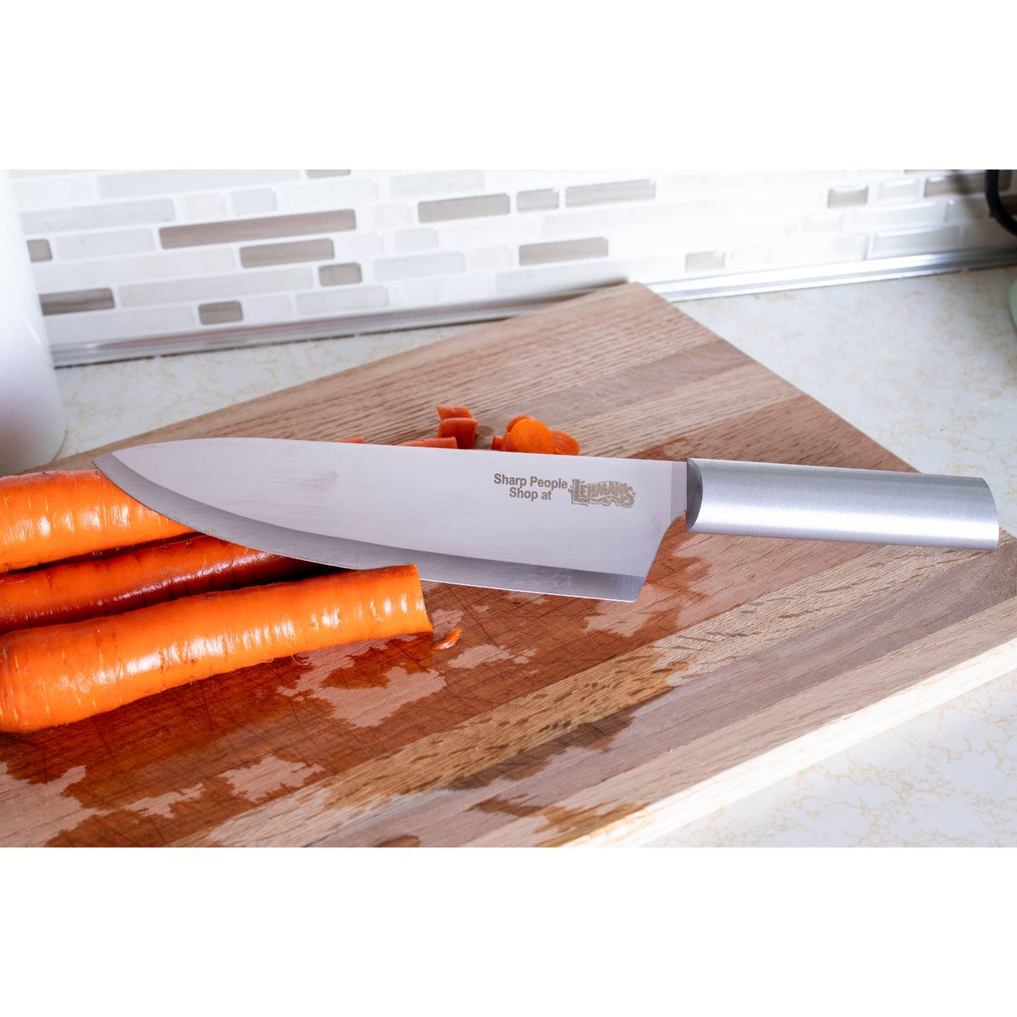 Kitchen chef's knife with stainless steel handle slicing fresh carrots on a wooden cutting board from kitchenware collection