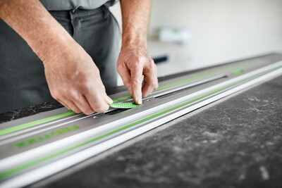 Person installing a green-accented guide rail on a workbench for precise woodworking tool accessory use