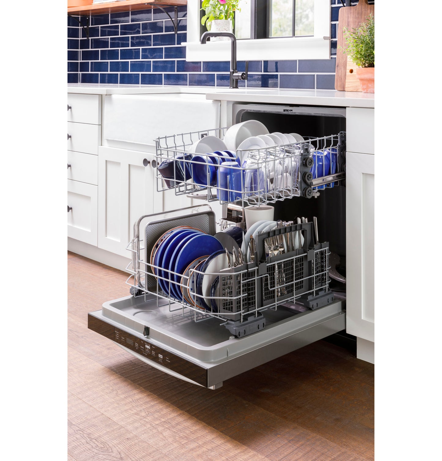 Open dishwasher with upper and lower racks loaded with dishes in kitchen featuring blue tile backsplash and white cabinetry